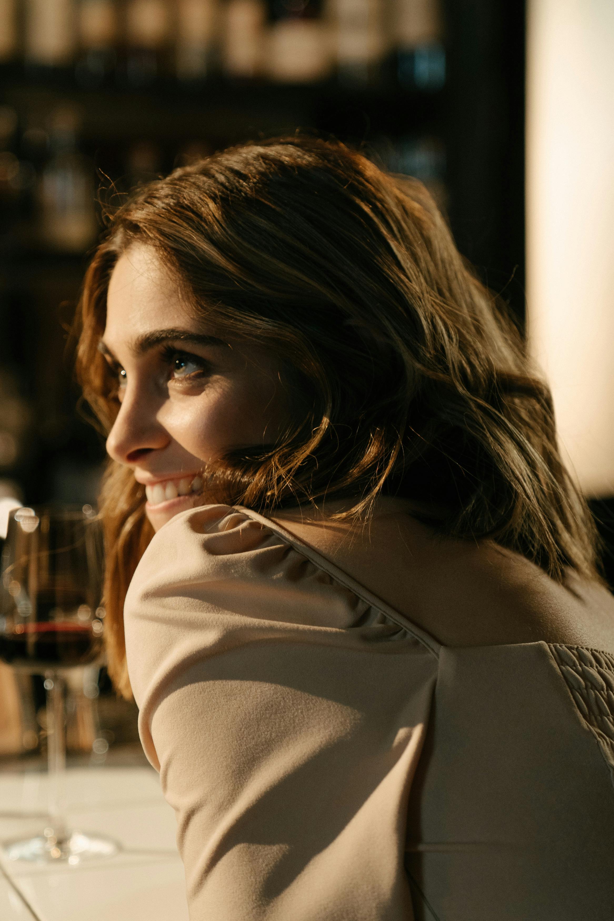 Smiling woman looking back over her shoulder in a warmly lit bar